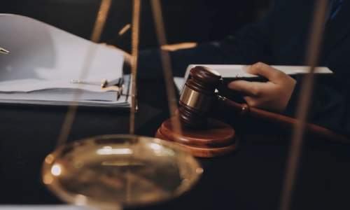 A lawyer and his client meeting in an office, with an out of focus scale in the foreground.