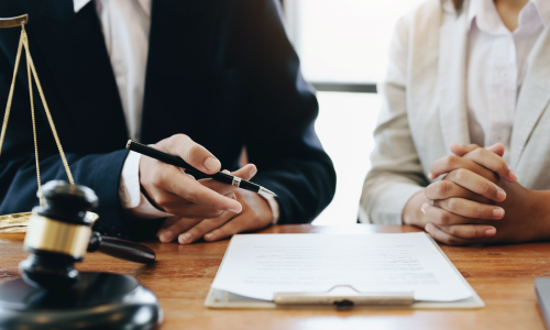 Dementia planning lawyer pointing to estate planning paperwork for a client with gavel and scales on the desk.