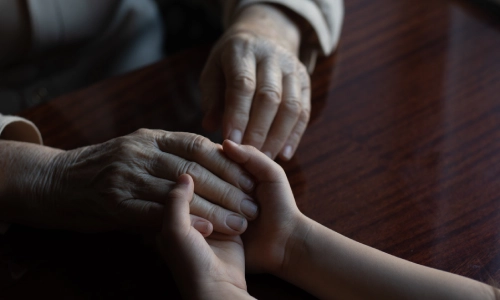 Elderly patient holding grandchild's hands