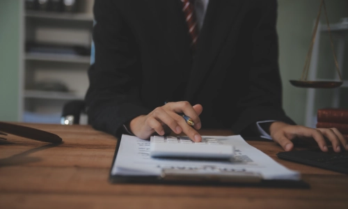 An estate tax planning lawyer seated at a desk and calculating the value of assets.