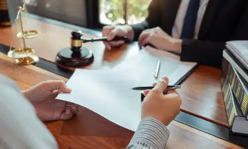 Dementia planning lawyer holding a gavel beside legal documents and scales of justice on a wooden desk.