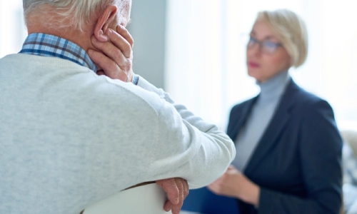 Back view of a senior man speaking with a young woman in a lawyer’s suit.