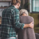 A young man is assisting an elderly woman as she walks.