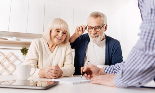 A happy elderly couple discussing with a social security legal team over coffee at a table.