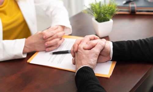 A close-up of an elderly man and woman, each of them had their hands clasped together.