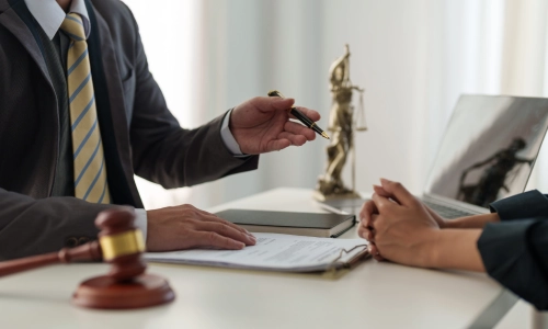 A Burlington County trusts and estates lawyer holding a pen in his left hand while speaking to a client sitting across a table