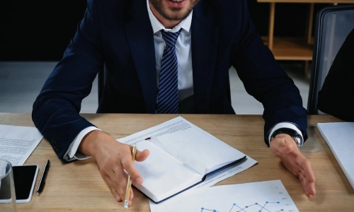 A Cranbury trusts and estates lawyer gestures with both hands while discussing the contents of a document on n office table