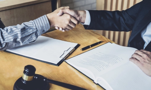 A Highland Park trusts and estates lawyer shaking hands with a client while two documents lie on a table between them