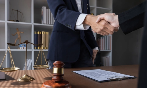 A Hopewell trusts and estates lawyer standing in front of a colleague with an office desk in between them as they shake each other's hands