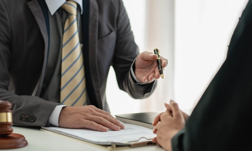 A Lambertville trusts and estates lawyer gestures with a pen in their left hand while speaking with a colleague about a trusts and estates concern