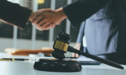 A Lawrence trusts and estates lawyer shaking hands with a colleague in the background with a hammer and gavel in closer view