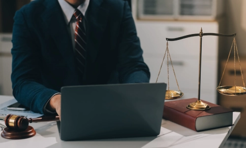A Medford trusts and estates lawyer working on a black laptop placed on an office table beside a book and balance scales