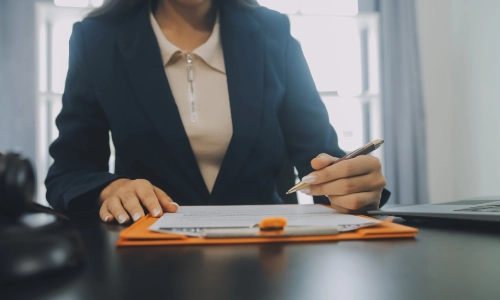 A montgomery trusts and estates lawyer is signing a contract and sitting at her office desk inside a law office
