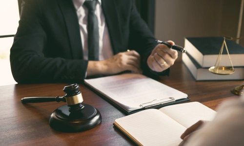 A trusts and estates lawyer serving Mount Laurel handing a pen over to a client sitting on the oppositte side of an office desk