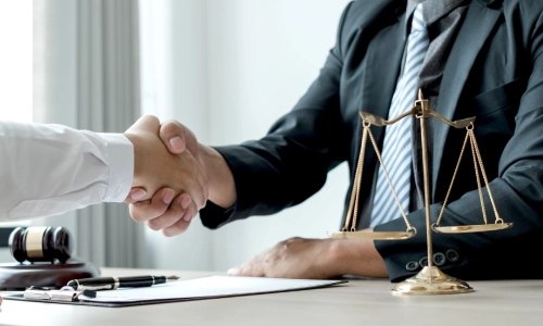 A Pennington trusts and estates lawyer shaking hands with a client after signing a contract placed on the table between them