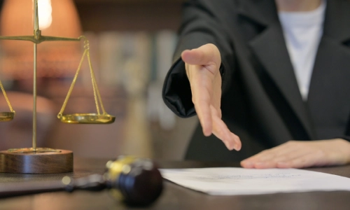 A trusts and estates lawyer serving Princeton sitting in a law office holds her hand out forward for a handshake