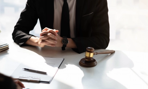 A Somerset County elder law attorney sits with hands clasped together as they speak with a client on the opposite side of a table