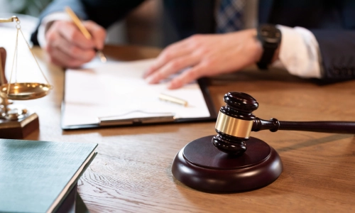 A Somerset County probate lawyer signing a legal documetn while leaning over the office desk
