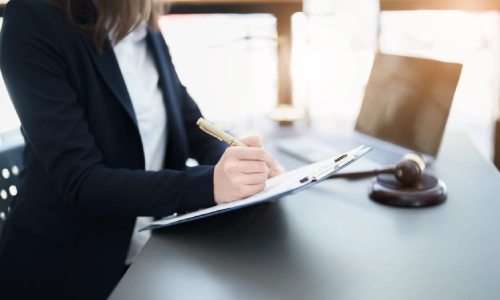 A South Brunswick trusts and estates lawyer writing on a clipboard while sitting in front of a laptop placed on an office desk