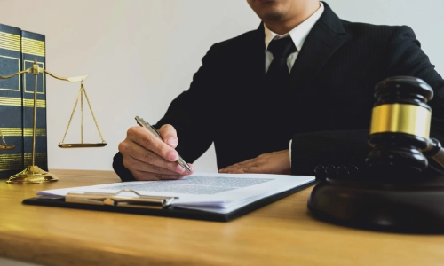 A West Windsor trusts and estates lawyer looks down at a document on the table while writing with a pen