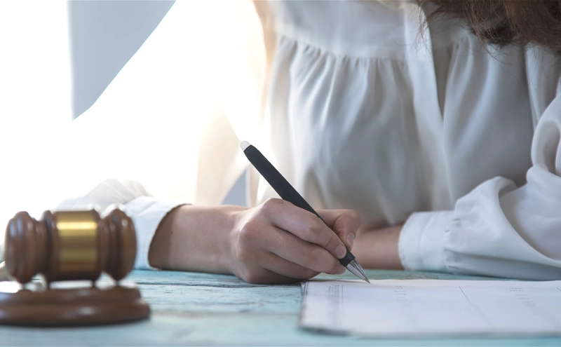 An estate planning lawyer at her table next to a gavel reviewing a document.