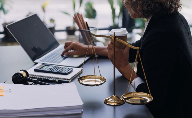 An estate planning attorney working on a client's inheritance on her office laptop.